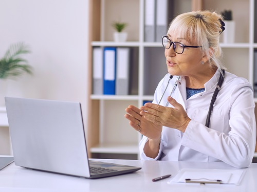 A life sciences healthcare professional explaining something on a live video call on a laptop